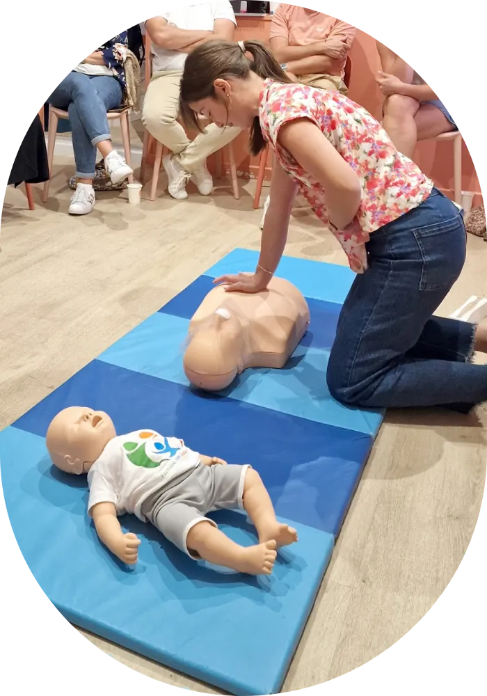 Une participante s'entraîne aux gestes de premiers secours sur un mannequin, pendant l'atelier secourisme enfants